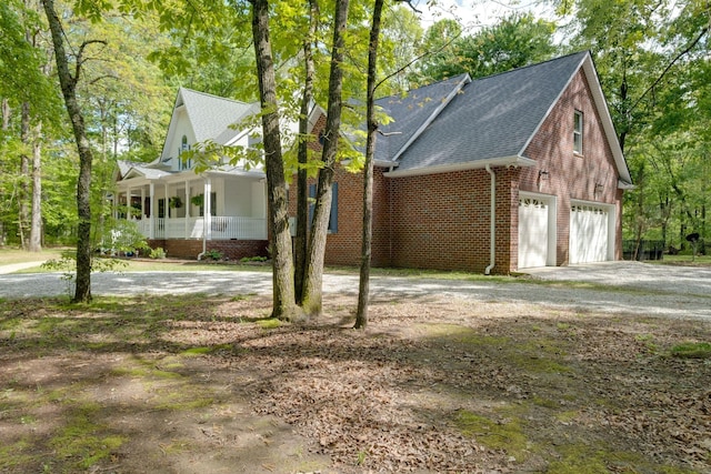 view of front of property featuring driveway, brick siding, roof with shingles, and covered porch