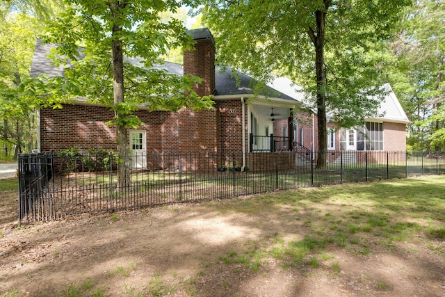 back of property featuring a fenced front yard, brick siding, and a chimney