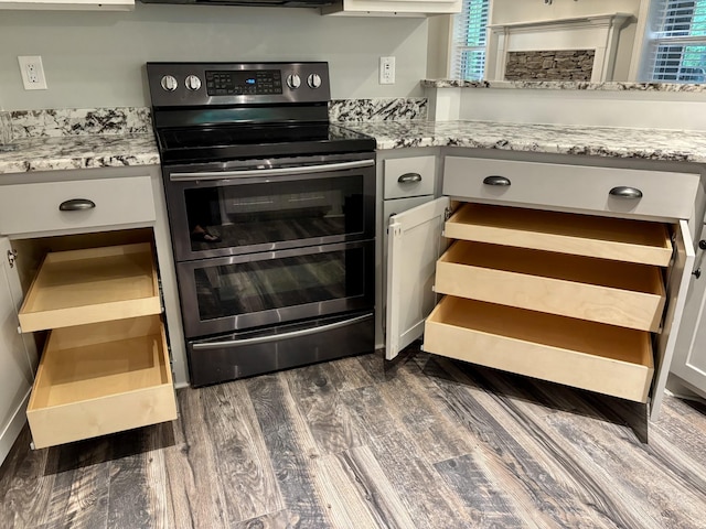 kitchen with dark wood finished floors, light stone counters, and double oven range