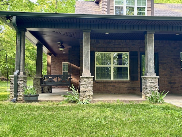 view of exterior entry with a porch, a yard, and brick siding