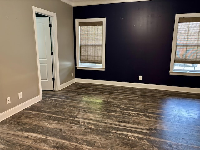 spare room featuring baseboards and dark wood finished floors