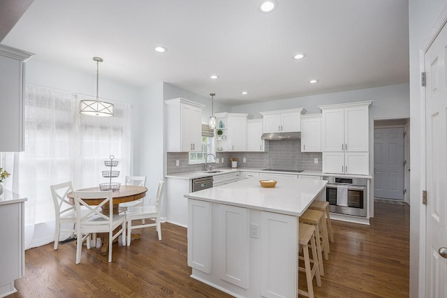 kitchen featuring under cabinet range hood, light countertops, dark wood-style floors, white cabinets, and appliances with stainless steel finishes