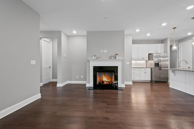 2131 Gunwale Mews, Franklin, TN 37064 - unfurnished living room featuring dark wood finished floors, recessed lighting, baseboards, a warm lit fireplace, and a sink