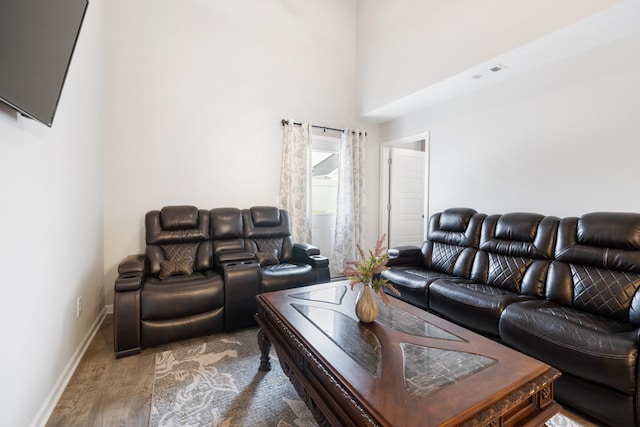 living area featuring wood finished floors, baseboards, and a high ceiling