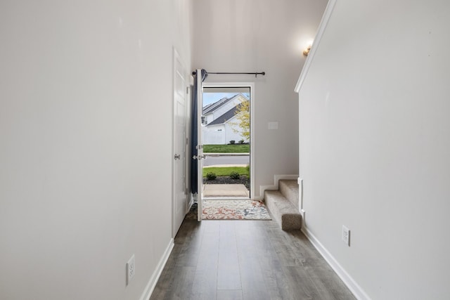 entryway with wood finished floors, baseboards, and stairs