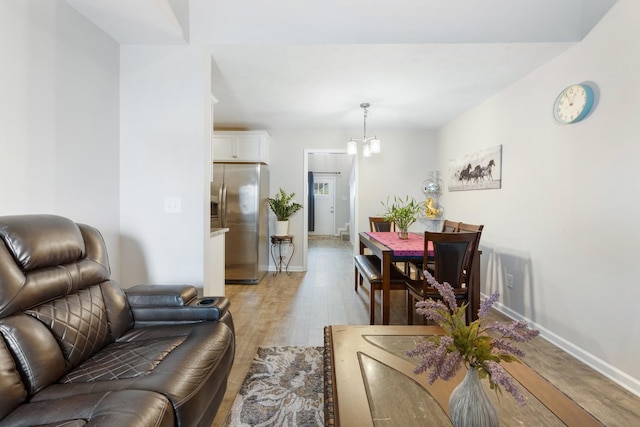 interior space featuring baseboards, a notable chandelier, and light wood-style floors