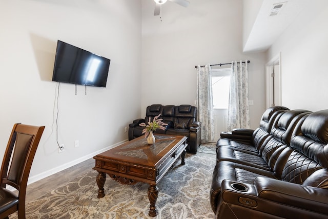 living area featuring baseboards, a ceiling fan, visible vents, and wood finished floors