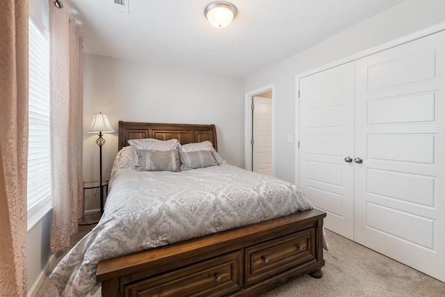 bedroom featuring a closet, light carpet, and visible vents