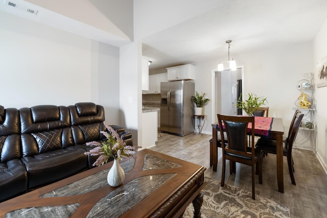living room with light wood-type flooring, baseboards, and visible vents