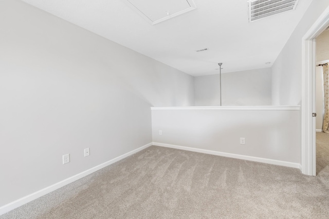 carpeted empty room with baseboards, attic access, and visible vents