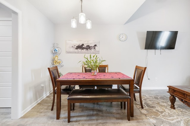 dining room featuring baseboards, vaulted ceiling, a notable chandelier, and wood finished floors