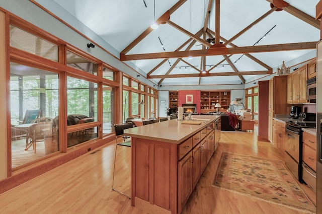 kitchen with stainless steel appliances, light wood-style flooring, open floor plan, light countertops, and a kitchen island