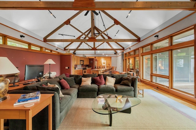 living room featuring track lighting, beam ceiling, and high vaulted ceiling