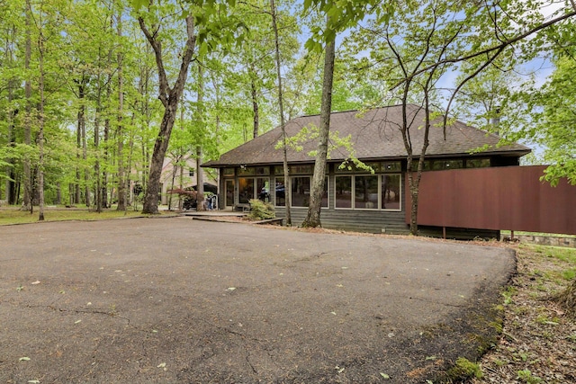 back of property featuring roof with shingles and driveway