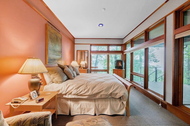 carpeted bedroom featuring multiple windows, ornamental molding, and access to outside