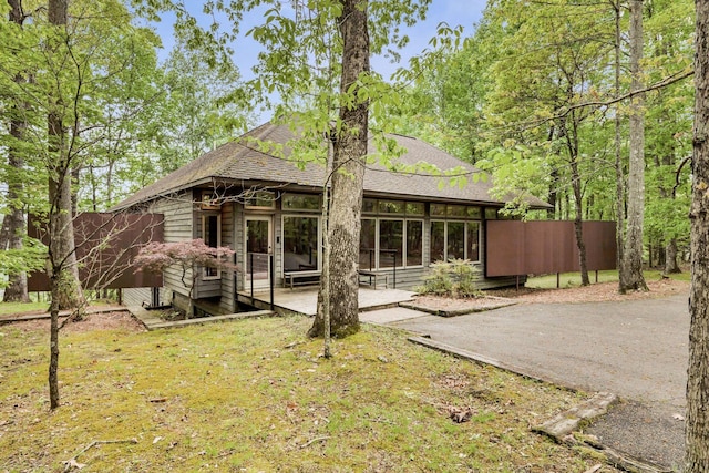 back of property with fence and a shingled roof
