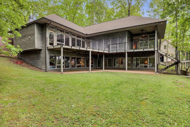 back of property with a yard, a patio area, a shingled roof, and stairway