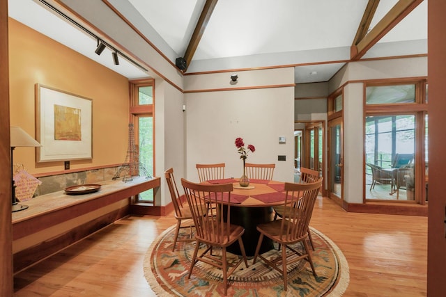 dining room with baseboards, lofted ceiling with beams, and light wood-style flooring