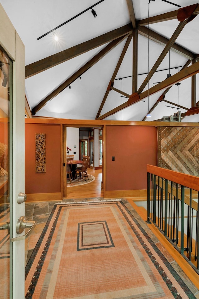 corridor with rail lighting, baseboards, beamed ceiling, and high vaulted ceiling