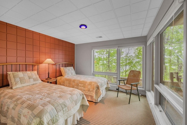 bedroom featuring multiple windows, light carpet, tile walls, and visible vents
