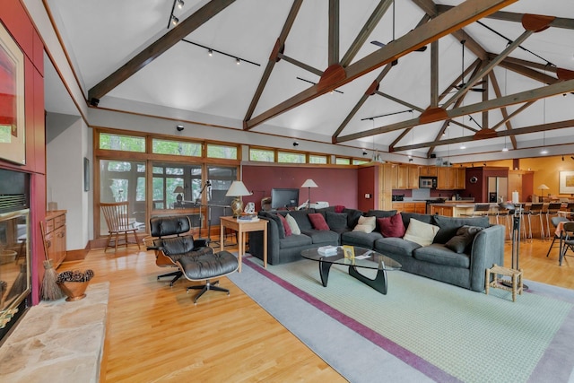 living room with rail lighting, light wood finished floors, and high vaulted ceiling