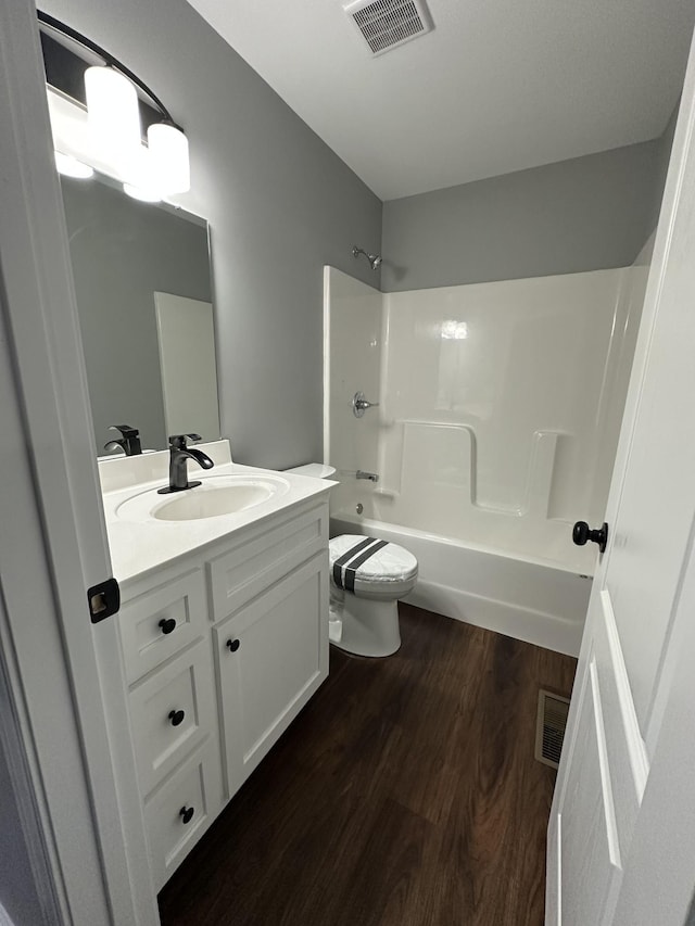 bathroom featuring toilet, wood finished floors, shower / bath combination, visible vents, and vanity