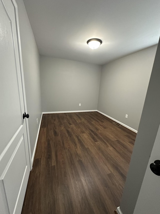 spare room with dark wood-type flooring and baseboards