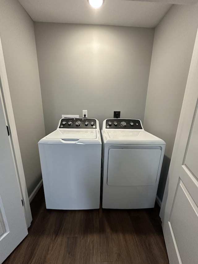 clothes washing area with washing machine and clothes dryer, dark wood finished floors, and laundry area