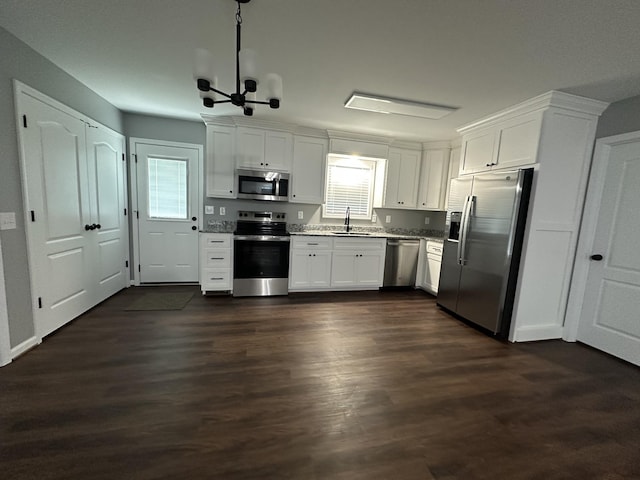 kitchen with a sink, dark wood finished floors, white cabinetry, appliances with stainless steel finishes, and a chandelier