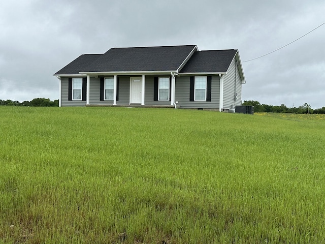ranch-style home featuring covered porch, central AC unit, and a front yard