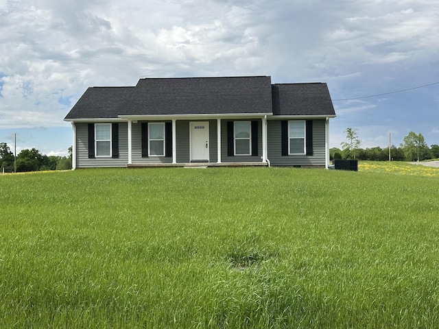 view of front facade featuring a front yard, a shingled roof, and covered porch