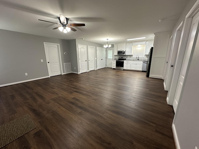unfurnished living room with dark wood-style flooring, ceiling fan with notable chandelier, baseboards, and visible vents