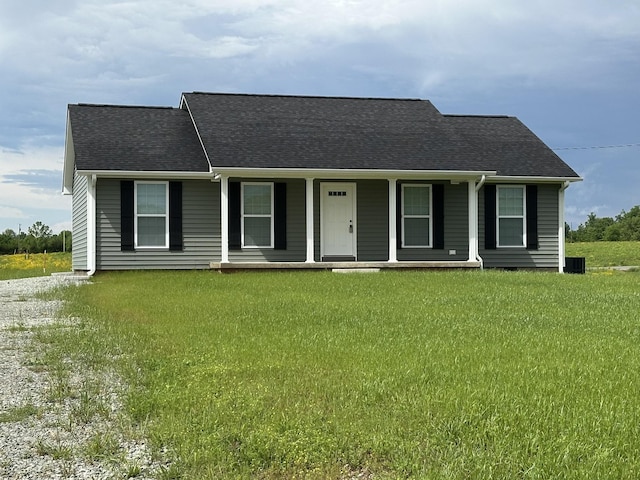 single story home with covered porch, a shingled roof, and a front yard