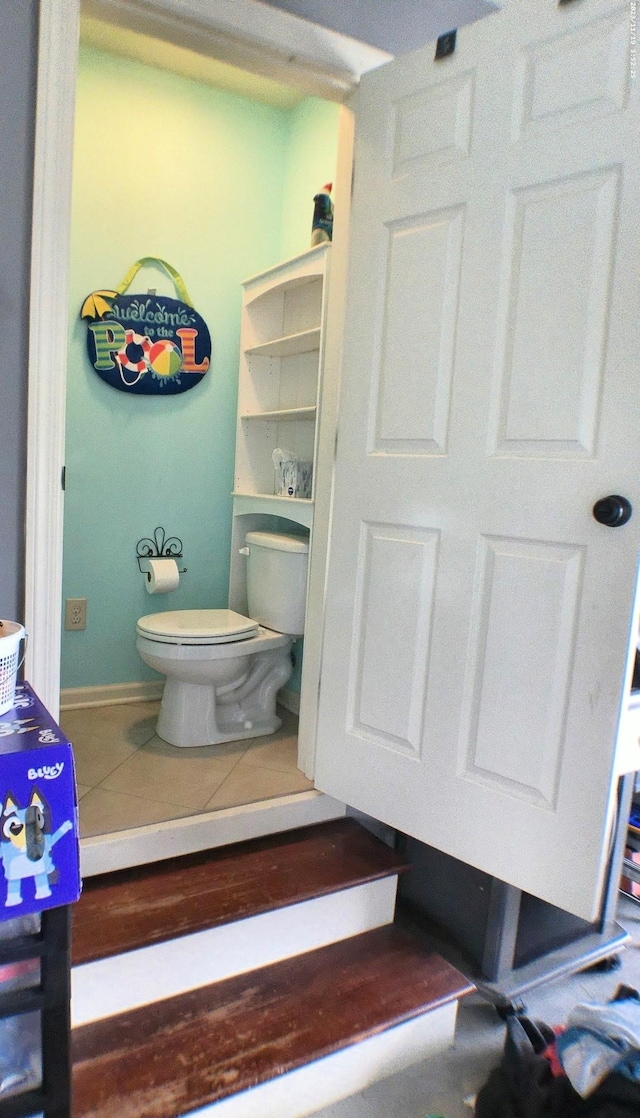 bathroom with toilet, baseboards, and tile patterned floors
