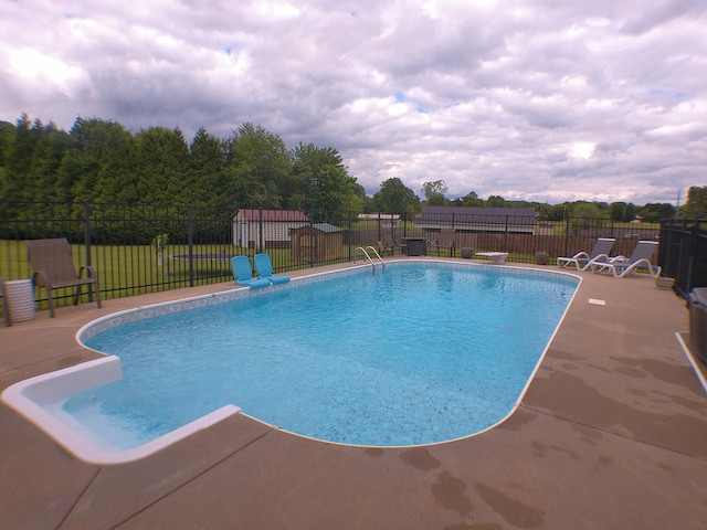 view of swimming pool featuring a yard, a patio area, a fenced in pool, and fence