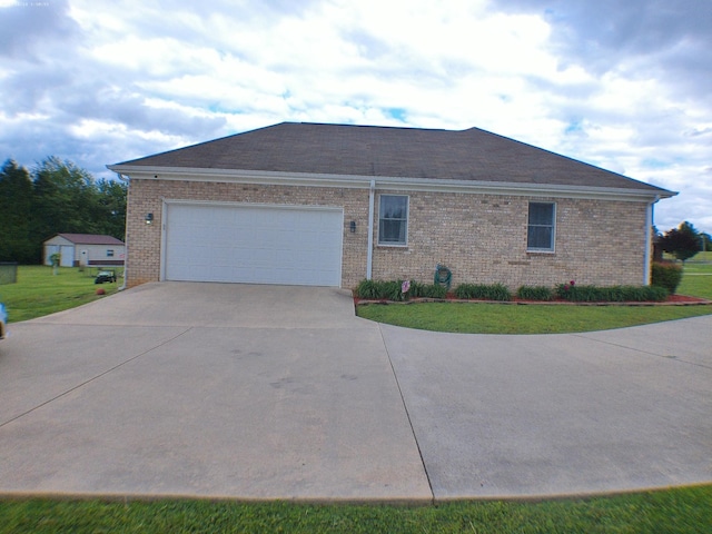 view of side of home featuring a yard, concrete driveway, an attached garage, and brick siding