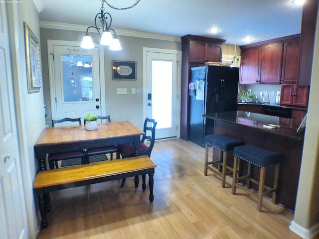 dining room with an inviting chandelier, ornamental molding, and light wood-type flooring