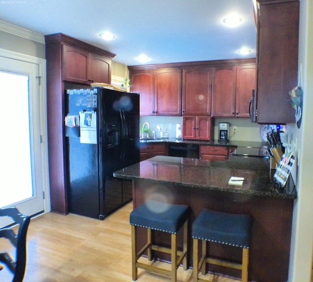 kitchen featuring a sink, a peninsula, ornamental molding, black appliances, and reddish brown cabinets