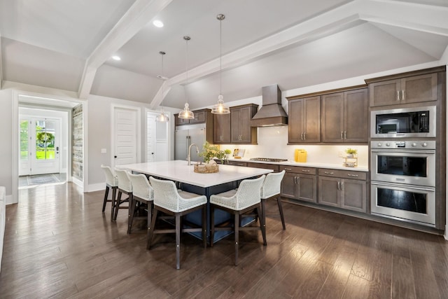 kitchen with built in appliances, custom range hood, a kitchen bar, light countertops, and an island with sink