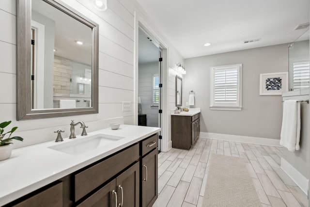 full bath featuring visible vents, two vanities, and a sink