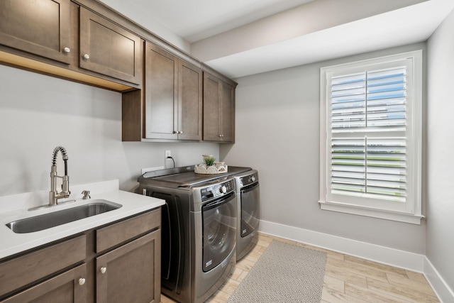washroom with washer and dryer, light wood finished floors, a sink, cabinet space, and baseboards
