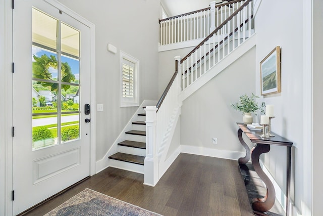 entrance foyer featuring a towering ceiling, dark wood-style flooring, baseboards, and stairs