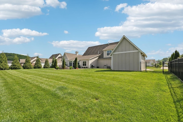 rear view of property with a yard, board and batten siding, and fence