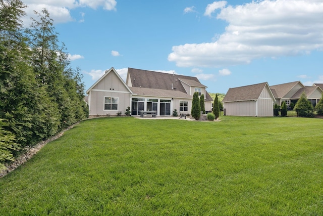 back of property featuring a yard, a patio area, an outbuilding, and a sunroom