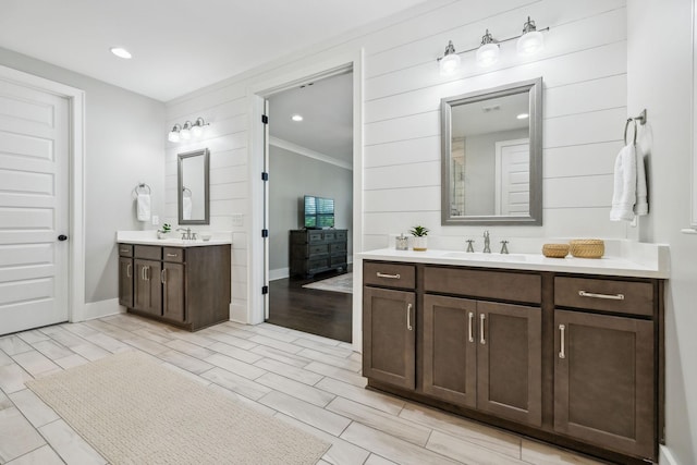 bathroom featuring a sink, wood finish floors, two vanities, and baseboards