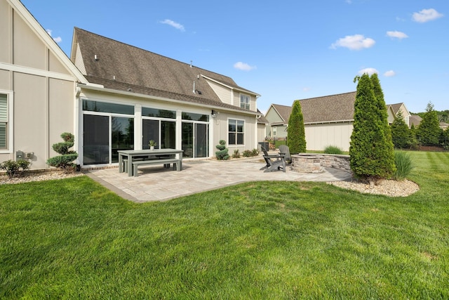 rear view of property with an outdoor fire pit, a yard, a patio, and a shingled roof