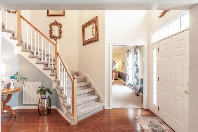 entrance foyer featuring baseboards, stairway, visible vents, and wood finished floors