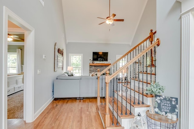 stairs featuring ornamental molding, ceiling fan, plenty of natural light, and high vaulted ceiling