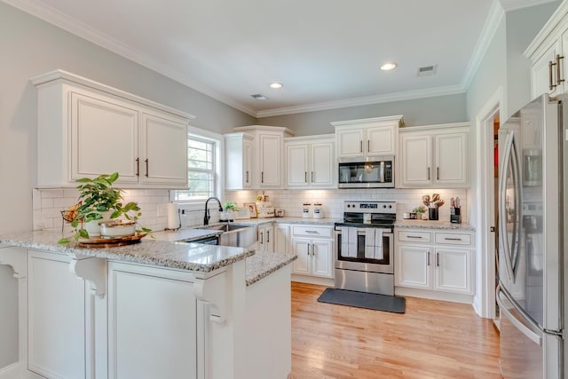 kitchen featuring a sink, a peninsula, appliances with stainless steel finishes, white cabinets, and light wood-style floors