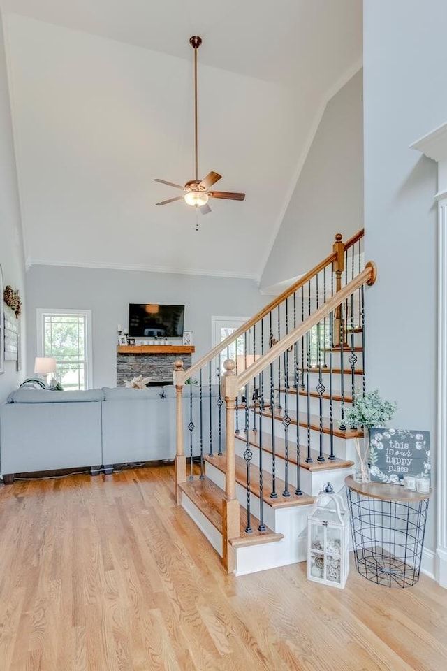 stairs featuring a ceiling fan, high vaulted ceiling, and wood finished floors